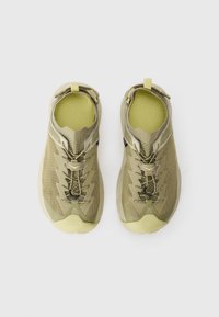 Adidași verzi deschiși, cu un superior din plasă texturată, șireturi elastice și o talpă cu amortizare. Include o buclă la călcâi pentru un îmbrăcăre ușoară.