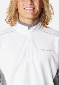 Weißer Fleece-Pullover mit grauem Kragen, Viertelreißverschluss und Columbia-Logo. Verfügt über kontrastierende graue Seitenpaneele und Nahtdetails.