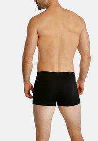 Black boxer shorts displayed from the back, featuring a smooth texture and a fitted design. The waistband is elastic and low-rise.
