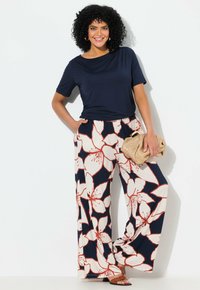 Námořnická halenka s krátkými rukávy, spárovaná s širokými kalhotami s květinovým vzorem v krémové a rezavé barvě. Tkaná kabelka a sandály.