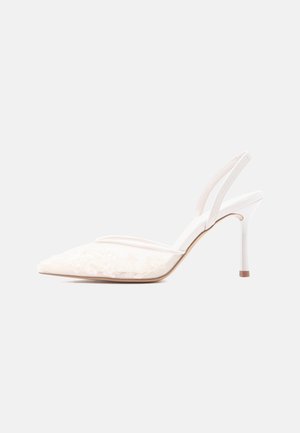 Valge kõrge kontsaga slingback-tald, terava varbaosaga, lillelise pitskatte ja kitsa kontsaga ühevärvilisel heledal taustal.