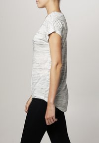 Svetle šedé tričko s jemným pruhovaným vzorem, krátkými rukávy, kulatým výstřihem a volným střihem, spojené s černými legínami.