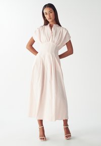 Triibuline midi kleit pehmes roosas ja valges, millel on lühikesed puhvärve, kinnine vöökoht ja voolav seelik, valmistatud kergest kangast.