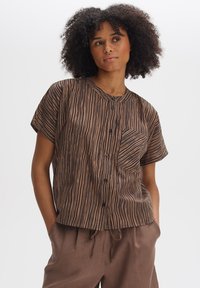 Brown button-up shirt with black vertical stripes, a round neckline, short sleeves, and a breast pocket. Worn with matching brown pants.