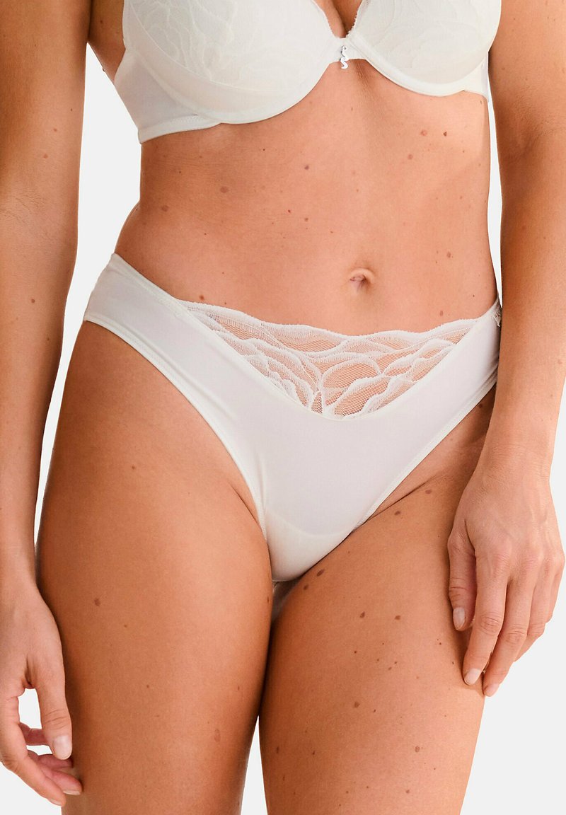 Witte ondergoed met kant afgewerkt, gemaakt van een zachte stof, met een hoge uitsnijding en een gestructureerd, gegolfd mesh bij de taille voor extra detail.