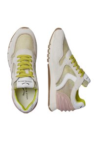 Die Sneakers haben ein beiges Wildlederoberteil mit Mesh-Panels, grünen Schnürsenkeln und einem weißen Logo. Die Gummisohle hat eine strukturierten braunen Unterseite.