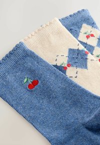 Zwei Paar Socken: eine hellblaue mit einem Kirschdesign und eine cremefarbene mit blauen Rauten und Kirschen, präsentiert vor einem neutralen Hintergrund.