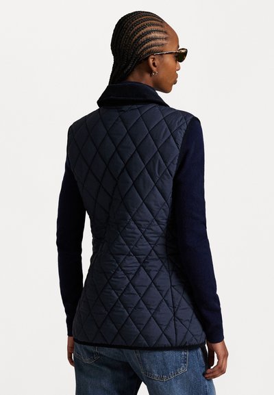 Marineblauwe gewatteerde vest met een schijnbare kraag en gebreide mouwen, met een aansluitende silhoutte, een textuurpatroon en contrasterend materiaal.