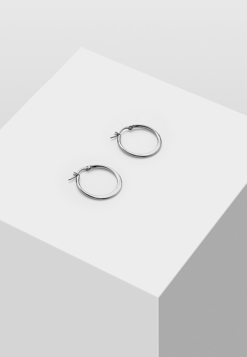 Silberne Creolen mit glänzender Oberfläche, die ein einfaches Verschlussdesign und ein kleines dekoratives Element aufweisen. Rund und gleichmäßig in der Form.