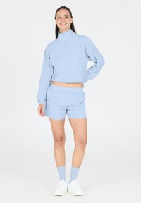 Helle blaue Sportbekleidung, bestehend aus einem kurz geschnittenen Pullover mit hohem Kragen und Shorts, gefertigt aus glattem Material; mit elastischen Taillenbündchen.