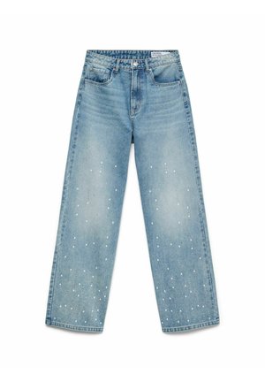 Gaiši zili džinsi ar platiem kāju galiem un augstu vidukli, ar baltām punktu apdari, kas izklāta pa kājām, un piecu kabatu dizainu.