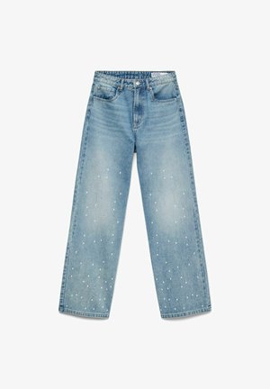 Gaiši zili džinsi ar platiem kāju galiem un augstu vidukli, ar baltām punktu apdari, kas izklāta pa kājām, un piecu kabatu dizainu.