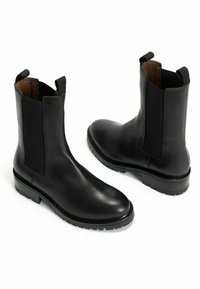 Black leather Chelsea boots with elastic side panels, rounded toes, and textured rubber soles. Features pull tabs for easy wear.