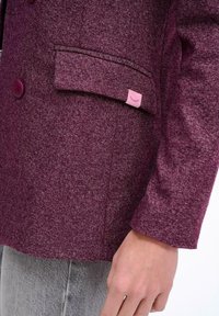 Burgundowy marynarka uszyta z tkaniny o strukturze, z kieszonką, z różową metką. Dwurzędowy fason z okrągłymi guzikami i dopasowanymi rękawami.