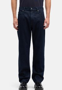 Granatowe dżinsy jeansowe o prostym kroju, z pięcioma kieszeniami, zapięciem na guziki oraz kontrastowymi szwami. Wykończone gładką teksturą.