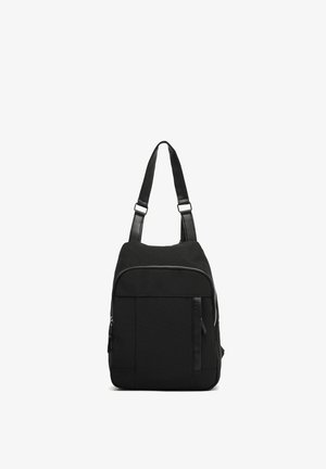 Sort rygsæk med et struktureret stof, justerbare stropper, lynlåsåbning foroven og en frontlomme med et slankt design og minimal hardware.