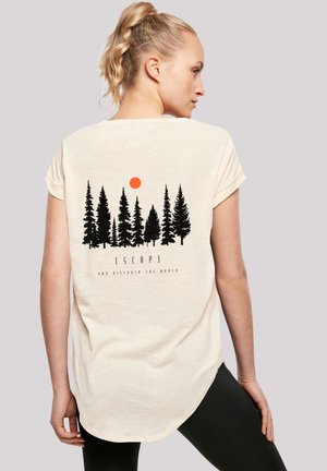 Blonde woman with ponytail wearing a cream t-shirt showing black pine trees and an orange sun graphic with "Escape and discover the world" text.