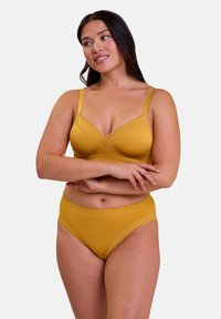 Ensemble de soutien-gorge et culotte jaune moutarde avec texture côtelée, bordure en dentelle, bretelles réglables et coupe classique sur le devant, présenté sur un fond blanc.