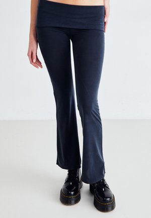Flared leggings in navy fabric with a wide waistband, paired with black lace-up platform boots featuring a textured sole.