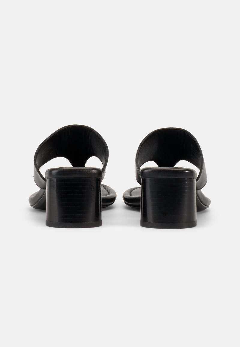 Schwarze Sandalen mit offener Ferse und niedrigen Blockabsätzen, von hinten auf weißem Hintergrund gesehen.