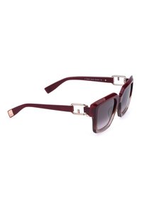 Lunettes de soleil carrées avec verres à dégradé foncé et montures épaisses rouge foncé avec des détails de charnières argentées.