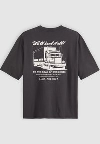 Camiseta negra con un gráfico blanco de un camión y el texto: "¡Lo transportaremos todo!" y los datos de contacto impresos en la parte posterior.