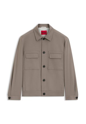 Herrenjacke in Taupe mit Knopfleiste, zwei aufgesetzten Brusttaschen mit Klappen, schwarzen Knöpfen und Kragen, präsentiert vor weißem Hintergrund.