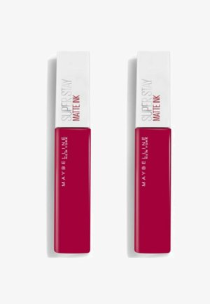 Rouge à lèvres liquide Maybelline Super Stay Matte Ink en rouge vif, avec un capuchon rectangulaire blanc portant un texte noir et un design élégant.