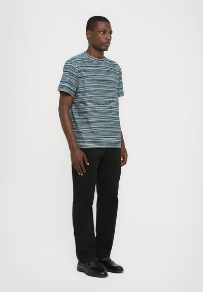 T-shirt à manches courtes rayé en bleu et blanc avec un col rond. Associé à un pantalon noir à jambe droite et des mocassins noirs.