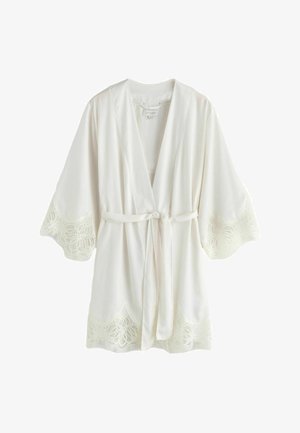 Biały szlafrok z koronkowym wykończeniem na rękawach i u dołu. Wykonany z miękkiego materiału, z wiązaniem w talii i otwartym przodem.