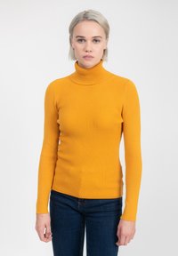 Maglione giallo a collo alto con maniche lunghe e design aderente. La trama è morbida e il colore è vivace su uno sfondo neutro.