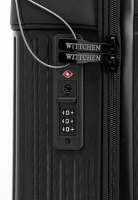 Czarna twarda walizka z zamkiem szyfrowym TSA ustawionym na 0-0-0, dwoma suwakami zamka oznaczonymi "WITTCHEN" oraz pętlą z drutu zabezpieczającego.