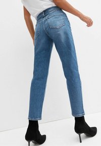 Blå denimjeans med rak passform, bakfickor, hög midja och fransad fåll i kombination med svarta stövletter med klack.