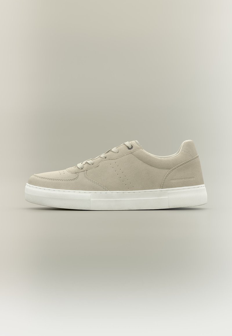 Baskets basses en daim beige clair avec semelle en caoutchouc blanc et fermeture à lacets, présentées de profil sur un fond neutre.