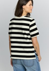 Zwart-witte gestreepte T-shirt gemaakt van zachte katoen, met korte mouwen, een ronde hals en zijsplitten aan de onderkant.