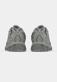 Sive atletske čevlje z teksturirano zgornjimi deli, strukturirano zasnovo, gelno blaženje in gumijastimi podplati, ki vključujejo mrežaste ventilacijske panele.