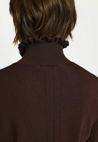 Pruun koeragami kaelusega kootud sviiter, millel on ribaline tekstuur ja volangiga krae. Omab puhtat, minimalistlikku disaini ja peeneid vertikaalseid õmblusdetailide.
