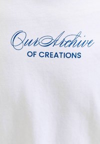 Λευκό ύφασμα με μπλε κείμενο που γράφει «Το Αρχείο μας» με καλλιγραφικά γράμματα πάνω από «OF CREATIONS» με κεφαλαία γράμματα.