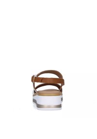Sandali in pelle marrone con più cinghie incrociate, una soletta imbottita e una suola bianca con un accento metallico alla base.
