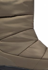 Bruine geïsoleerde laars van gequilt nylon, met een slanke vorm, subtiele stikdetails en een gestructureerde rubberen zool.