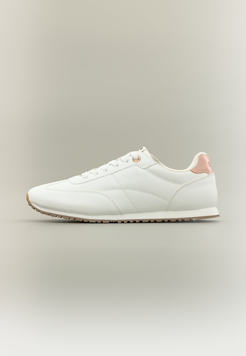 Λευκό χαμηλό αθλητικό παπούτσι με ανοιχτό ροζ ταμπελάκι στη φτέρνα, λευκά κορδόνια και μπεζ καουτσούκ σόλα σε ουδέτερο φόντο.