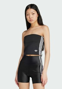 Čierny bandeau top s tromi bielymi pruhmi na boku, v kombinácii s čiernymi šortkami s vysokým pásom. Materiál vyzerá elasticky a priliehavo.