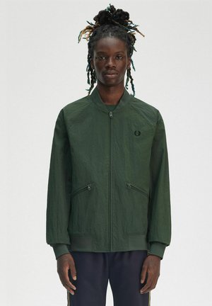 Giacca bomber verde realizzata in materiale leggero, con chiusura a zip frontale, due tasche con zip, polsini a costine e un logo sul petto.
