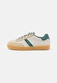 Sneakers with a light beige suede upper, green leather accents, white stripe design, gray laces, and a gum rubber sole.