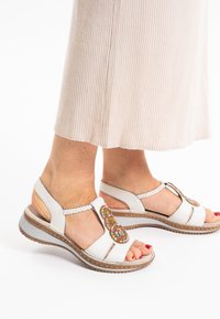 Weiße Sandalen mit geflochtenen Akzenten und bunten Perlenverzierungen. Verfügt über eine gepolsterte Sohle und ein offenes Zehendesign.