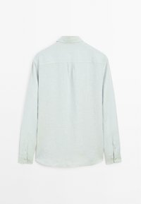 Chemise à manches longues bleu clair en tissu texturé, dotée d'un col, d'un empiècement au dos et de poignets à boutons.