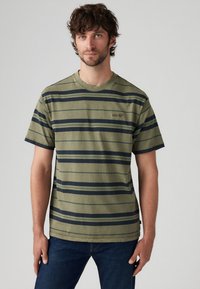 Grønstribet t-shirt lavet af bomuld. Har marineblå og lysere grønne horisontale striber, rund hals og korte ærmer. Mærke-logo på brystet.