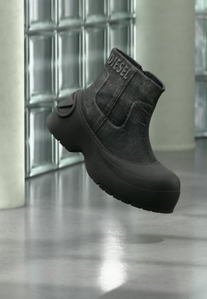 Черна платформа за глезена с лейбъл "DIESEL", текстурирана горна част, дебела подметка, показана плаваща над отразяващ под и стена от стъклени блокове.