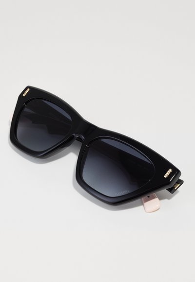 Óculos de sol oversized pretos com um design geométrico, lentes escuras e subtis detalhes em dourado nas armações. Braços texturizados com uma ponta rosa.