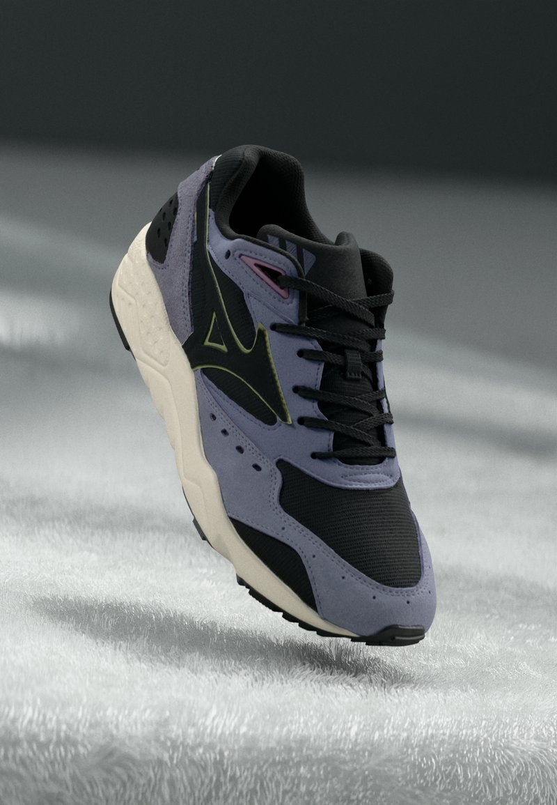 Lila és fekete sportcipő texturált velúrból és hálós panelekkel. Párnázott talppal, fekete fűzős megoldással és reflektáló részlettel rendelkezik.